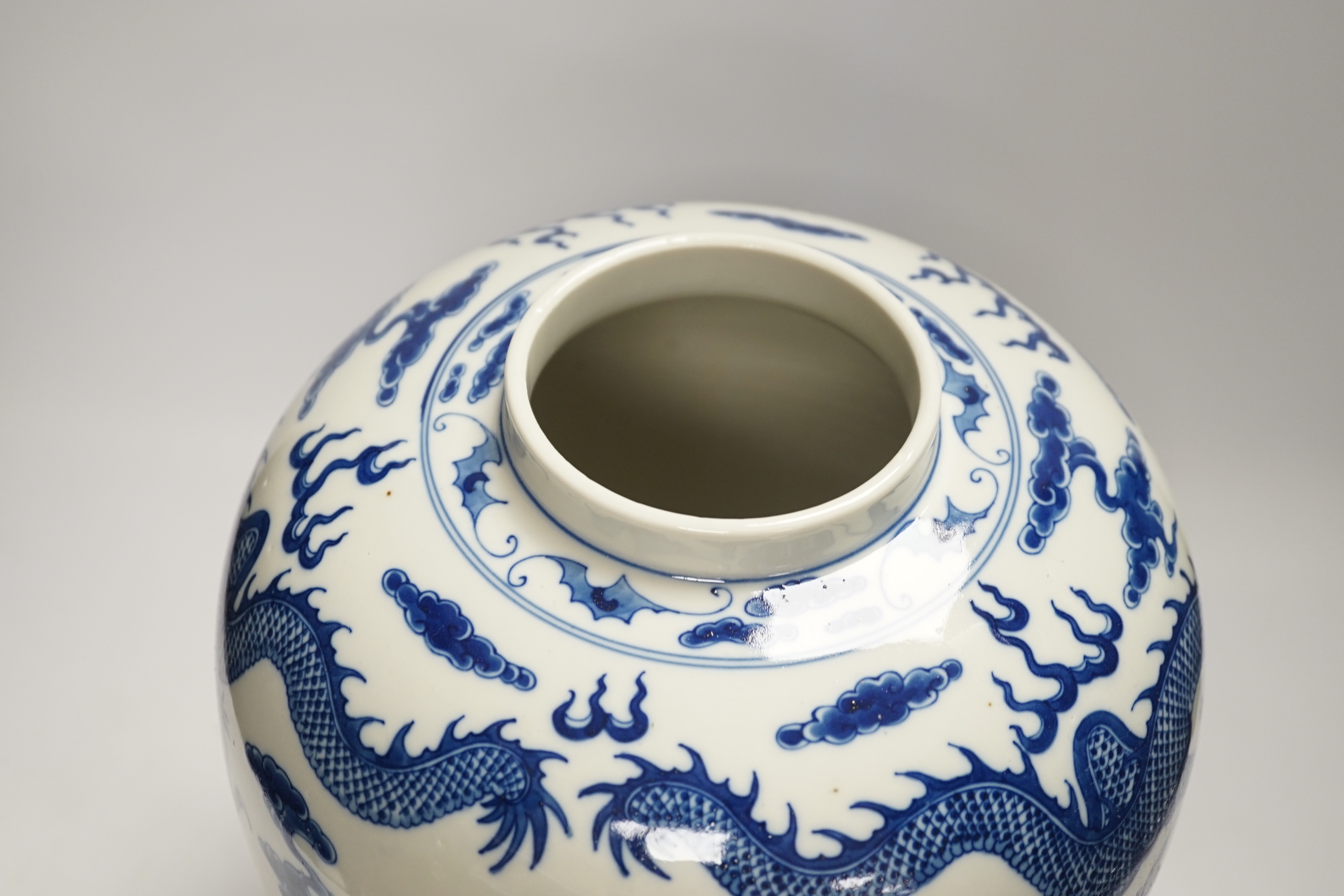 A large Chinese blue and white jar decorated with dragons chasing the flaming pearl together with unassociated carved wood lid and stand, 35cm high